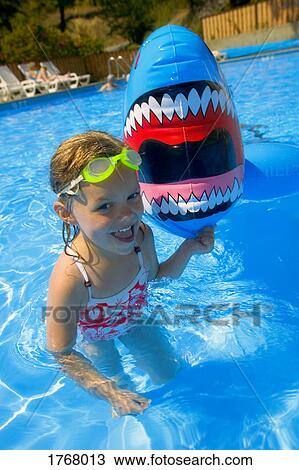 Girl playing in swimming pool with inflatable shark View Large Photo Image Stock Image - Girl playing in swimming pool with inflatable shark. Fotosearch
