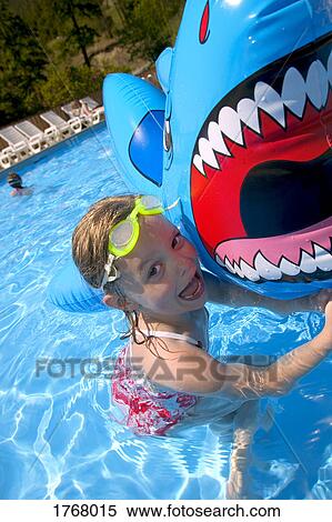 Stock Photography - Girl playing in swimming pool with inflatable shark. Fotosearch