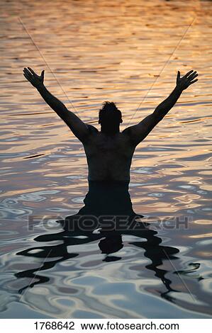 Stock Image - Man with arms raised in water. Fotosearch