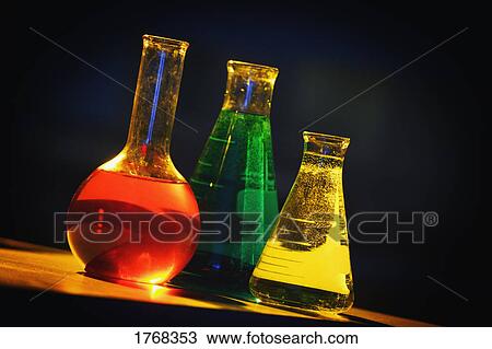 Stock Image - Measuring flasks containing chemicals. Fotosearch