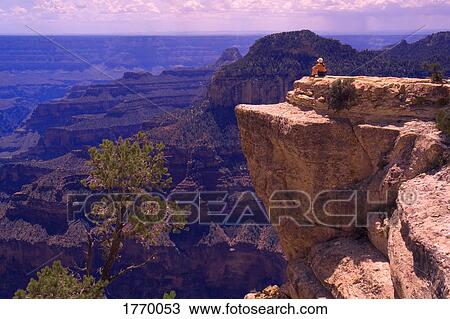 Stock Image - person sitting on rock outcrop. Fotosearch