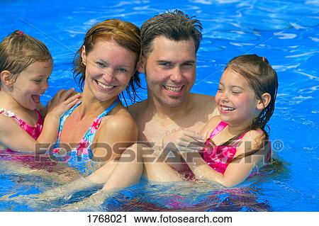 Stock Image - Portrait of a happy family in swimming pool. Fotosearch