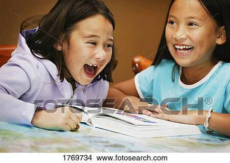 Two girls reading and giggling View Large Photo Image Picture - Two girls reading and giggling. Fotosearch