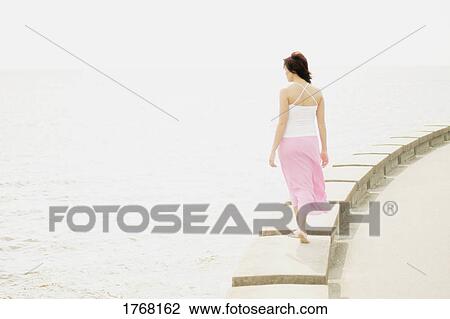 Stock Image - Woman walks on the edge. Fotosearch
