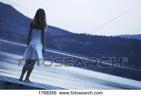 Young woman looking out over lake View Large Photo Image Stock Photograph - Young woman looking out over lake. Fotosearch
