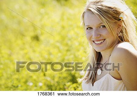 Young woman smiling sitting on the grass View Large Photo Image Stock Image - Young woman smiling sitting on the grass. Fotosearch
