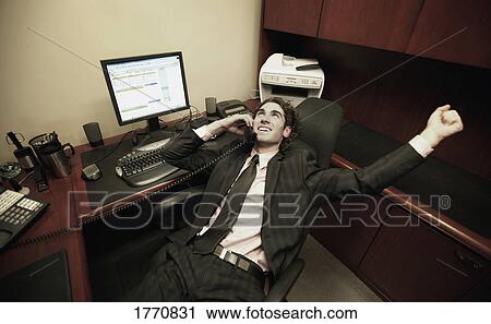 Stock Image - Business Man in office talking on phone. Fotosearch
