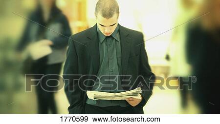 Stock Photo - Businessman walking and reading paper. Fotosearch