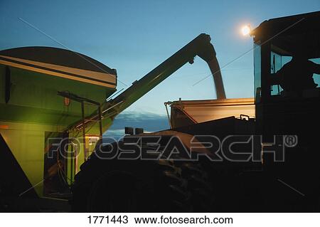 Stock Image - Farm machinery harvesting at night. Fotosearch