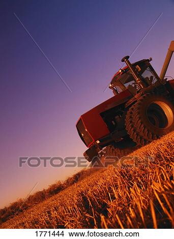 Farm tractor in field harvesting View Large Photo Image Picture - Farm tractor in field harvesting. Fotosearch