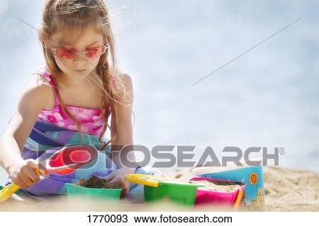 Stock Image - Girl building sand castle. Fotosearch