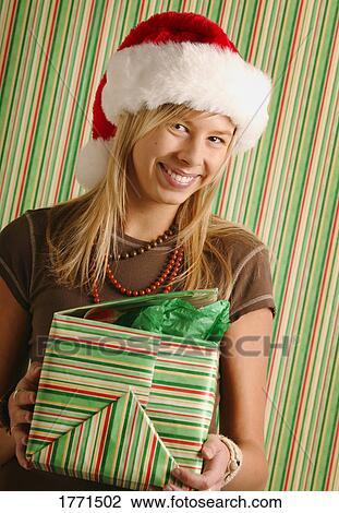 Stock Image - Girl opening Christmas gift. Fotosearch
