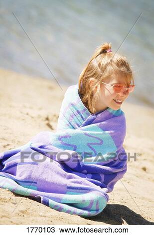 Girl sits on the beach in a towel View Large Photo Image Stock Image - Girl sits on the beach in a towel. Fotosearch