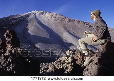 Stock Image - Hiker looking up at mountain. Fotosearch