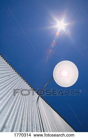 Picture - Light on outside building against sun sky. Fotosearch