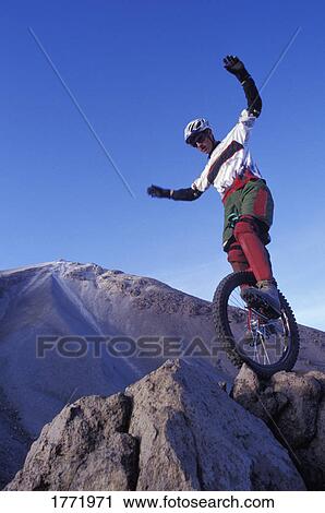 Man riding unicycle on rocks View Large Photo Image Stock Image - Man riding unicycle on rocks. Fotosearch