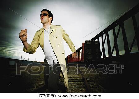 Stock Image - Man runs alongside a train. Fotosearch