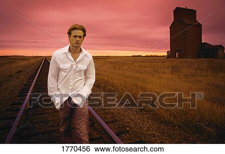 Stock Photograph - Man walking down railway track. Fotosearch
