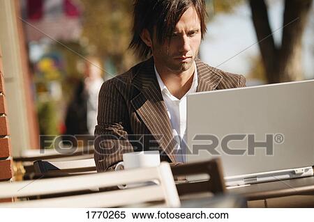 Man working on laptop at a cafe on the street View Large Photo Image Stock Photography - Man working on laptop at a cafe on the street. Fotosearch