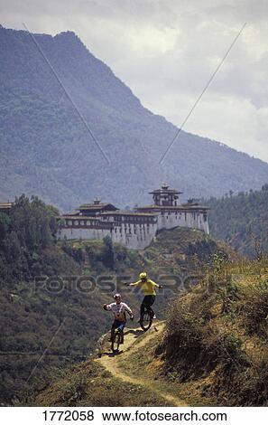 Unicyclists riding on path with old building in background View Large Photo Image Stock Photo - Unicyclists riding on path with old building in background. Fotosearch