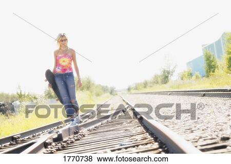 Stock Photo - Woman walking on train tracks. Fotosearch
