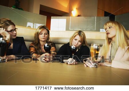 Stock Photo - Women at table with alcoholic drinks. Fotosearch