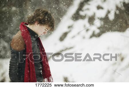 Young man standing as it snows View Large Photo Image Stock Photography - Young man standing as it snows. Fotosearch