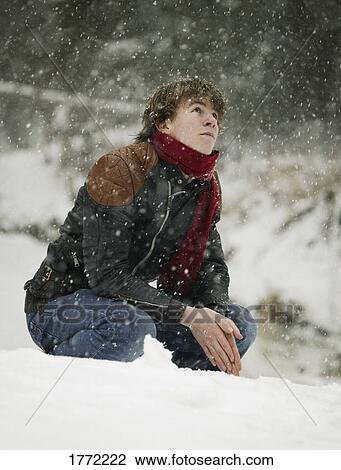 Stock Image - Young man waiting as it snows. Fotosearch