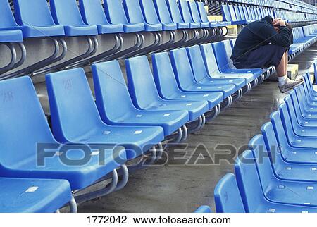 Young person with head in hands sitting in stadium View Large Photo Image Stock Image - Young person with head in hands sitting in stadium. Fotosearch