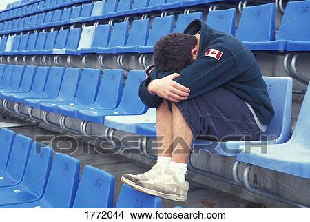 Young person with head on knees on stadium seat View Large Photo Image Picture - Young person with head on knees on stadium seat. Fotosearch