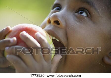 Stock Image - Child about to eat an apple. Fotosearch