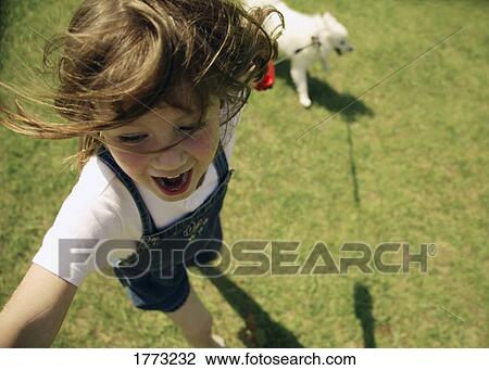 Stock Image - Child playing with her dog. Fotosearch