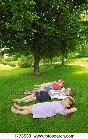 Children lying on grass View Large Photo Image Stock Photo - Children lying on grass. Fotosearch