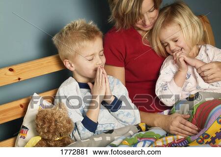 Stock Image - Children praying with mom. Fotosearch