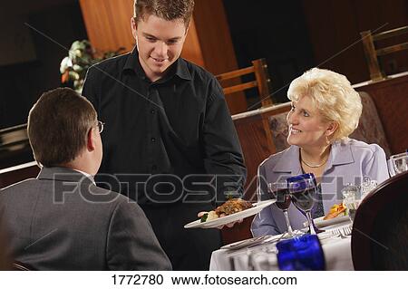Stock Image - Couple being served in a restaurant. Fotosearch