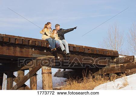 Family sitting on bridge View Large Photo Image Stock Image - Family sitting on bridge. Fotosearch