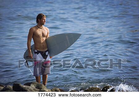 Stock Image - Surfer looking out to sea. Fotosearch