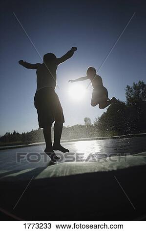 Stock Image - Two children jumping on a trampoline. Fotosearch