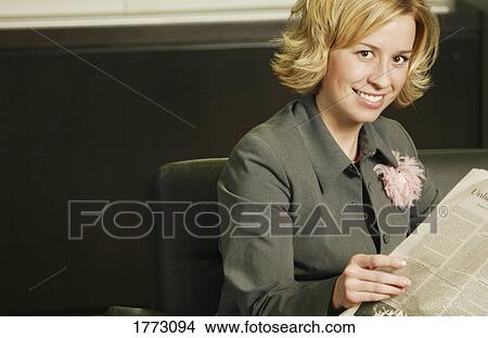 Picture - Woman looking up from newspaper. Fotosearch