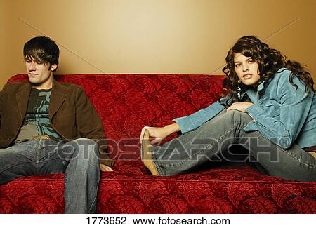 Young couple sitting on sofa View Large Photo Image Stock Image - Young couple sitting on sofa. Fotosearch