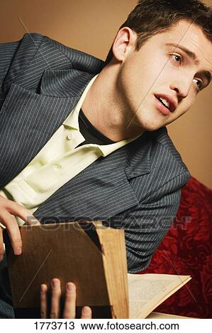 Stock Image - Young man holding book. Fotosearch