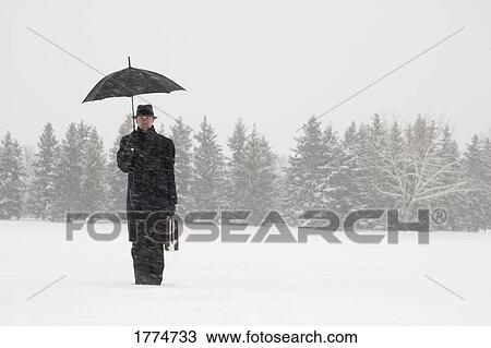 Stock Image - Businessman waiting in the snow. Fotosearch
