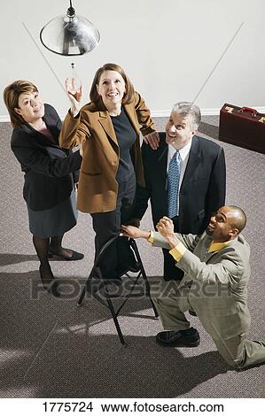 Picture - Businesspeople changing light bulb. Fotosearch