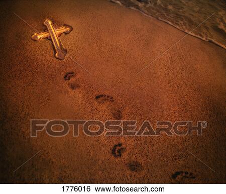 Stock Photograph - Footprints in the sand and a cross. Fotosearch