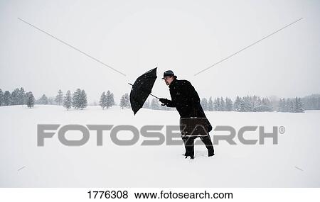 Stock Photo - Man battling against the snow. Fotosearch
