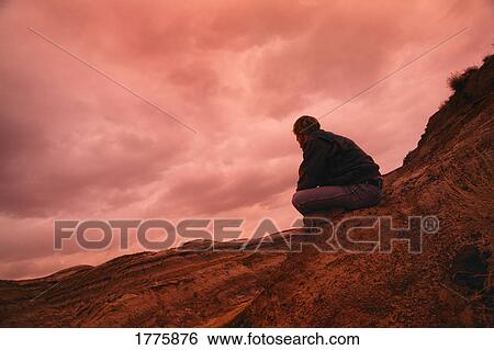 Stock Photograph - Man sitting on hill. Fotosearch