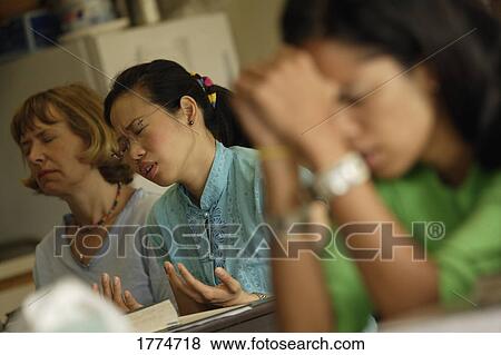 Stock Photo - People praying in a classroom. Fotosearch