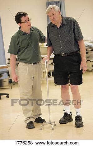 Stock Photo - Physiotherapist helping a patient to walk. Fotosearch
