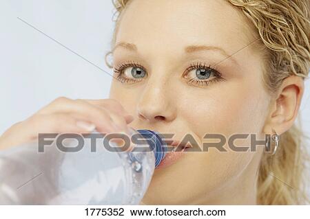Stock Image - Pretty girl drinking bottled water. Fotosearch