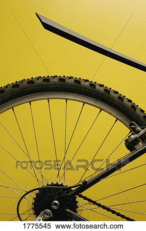 Stock Photography - Rear bicycle wheel against yellow background. Fotosearch